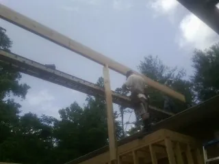 Carpenter setting a ridge beam over a new addition frame — Ice Dam Removal by Roofing Brothers in Eagle Lake