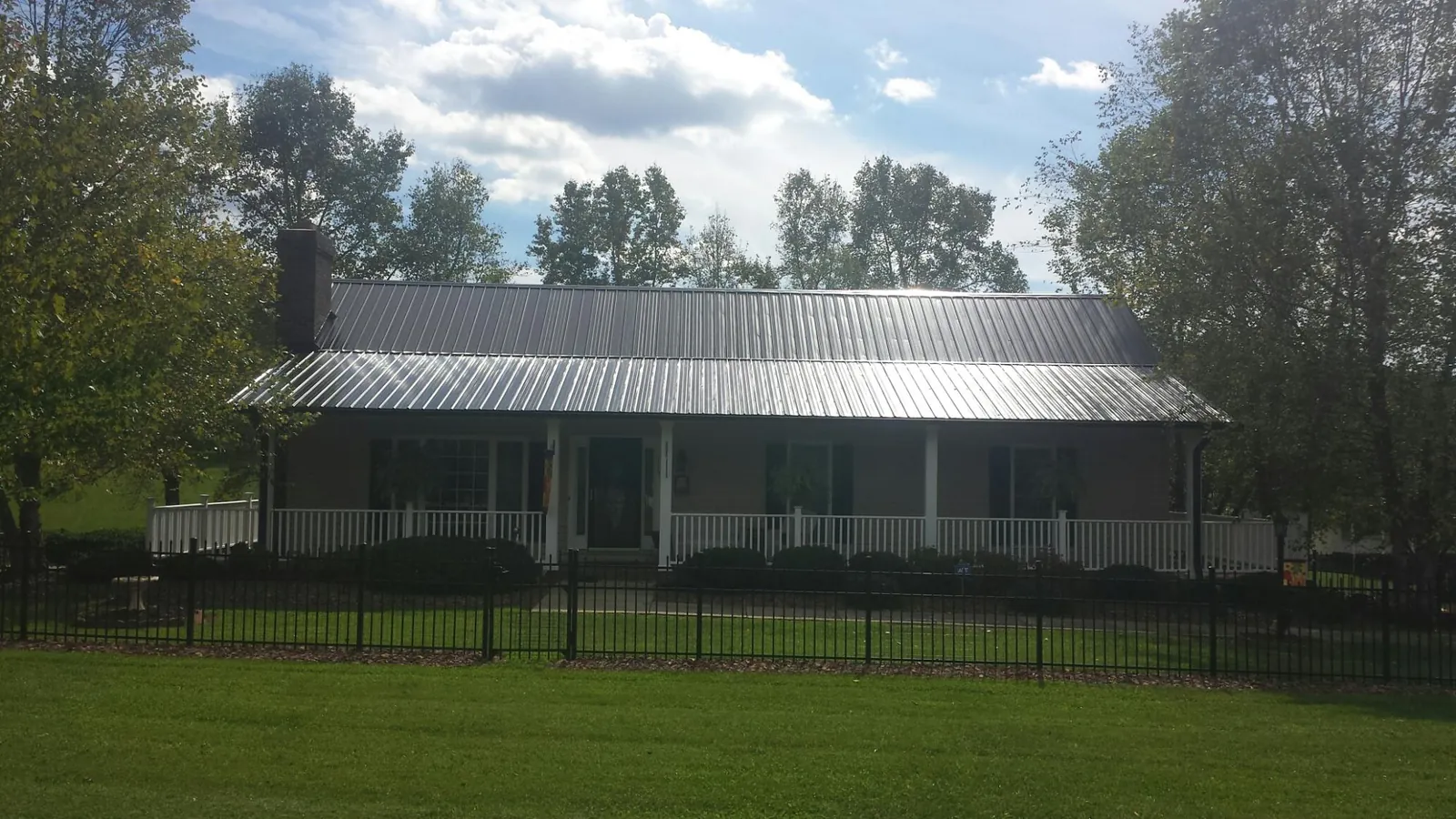 Gray metal roof on a brick ranch with a full width front porch — Gutter Guard Installation work by our crew in Eagle Lake