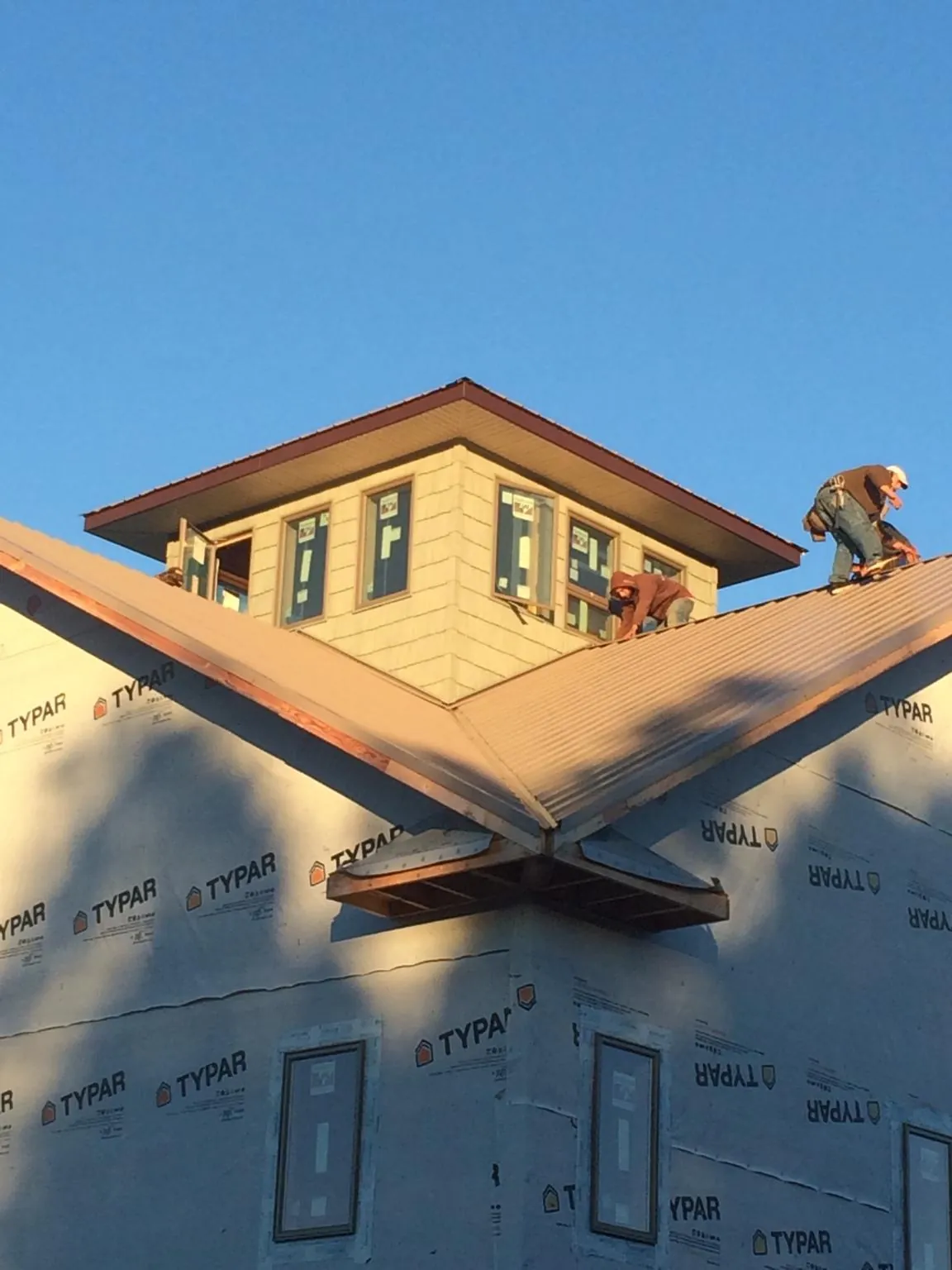 Roofers working around a rooftop cupola on a new metal roof at sunset — Roof Waterproofing in Eagle Lake by Roofing Brothers